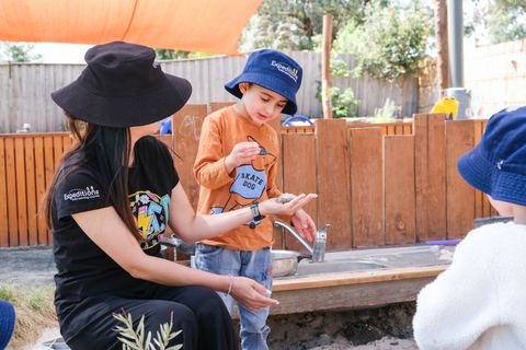 An educator supporting a child during outdoor play at Expeditions Narre Warren