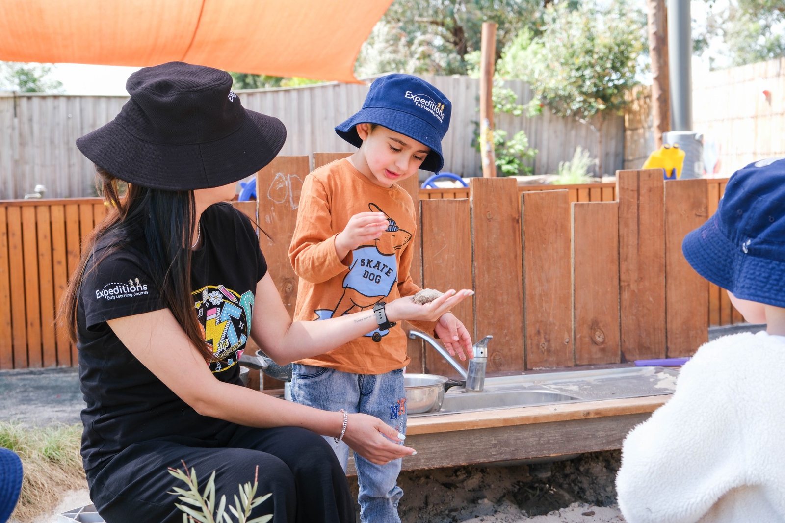 An educator supporting a child during outdoor play at Expeditions Narre Warren