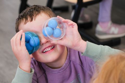 A child exploring with colourful viewing cups at Expeditions Officer