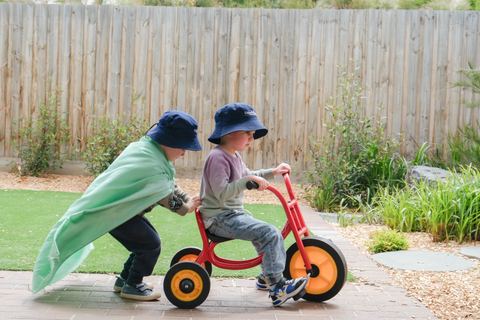 Children riding wheeled toys outdoors at Expeditions Officer