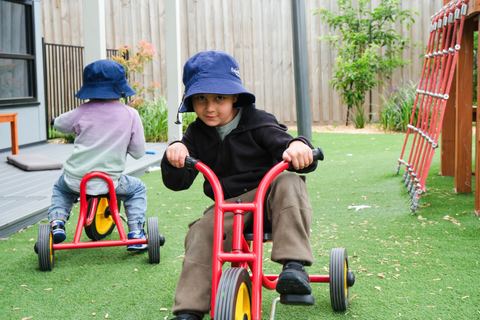 Children riding tricycles on an outdoor path at Expeditions Officer