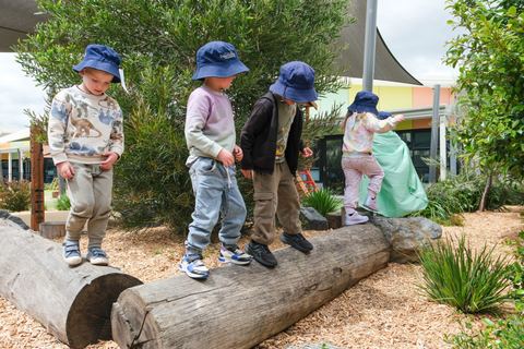 Children balancing on a log outdoors at Expeditions Officer