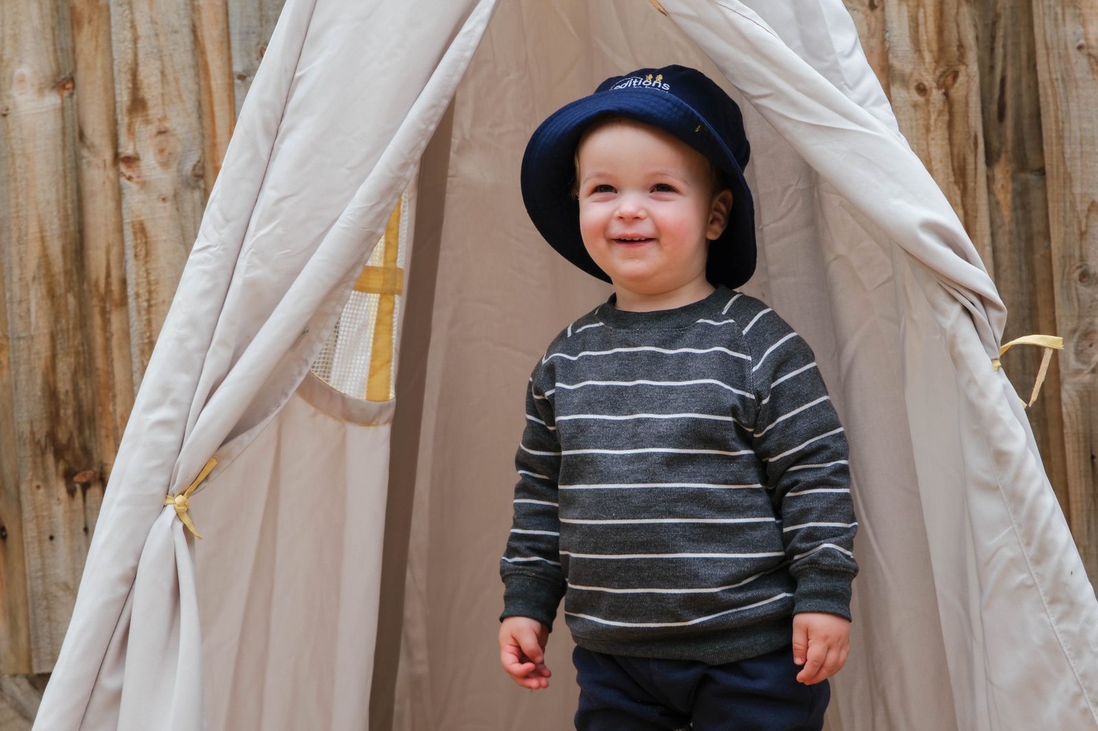 A child sitting in a fabric play tent at Expeditions Officer