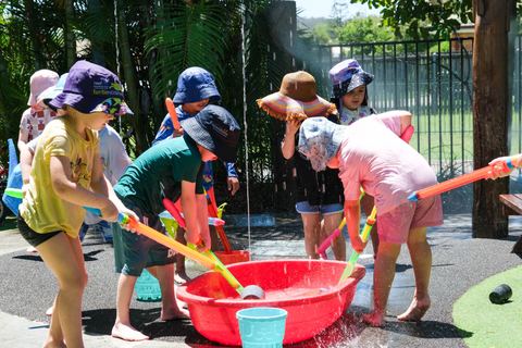 Children enjoying outdoor water play with buckets and channels at Expeditions Raceview