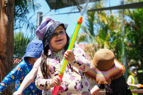 A child exploring water play with colourful equipment at Expeditions Raceview