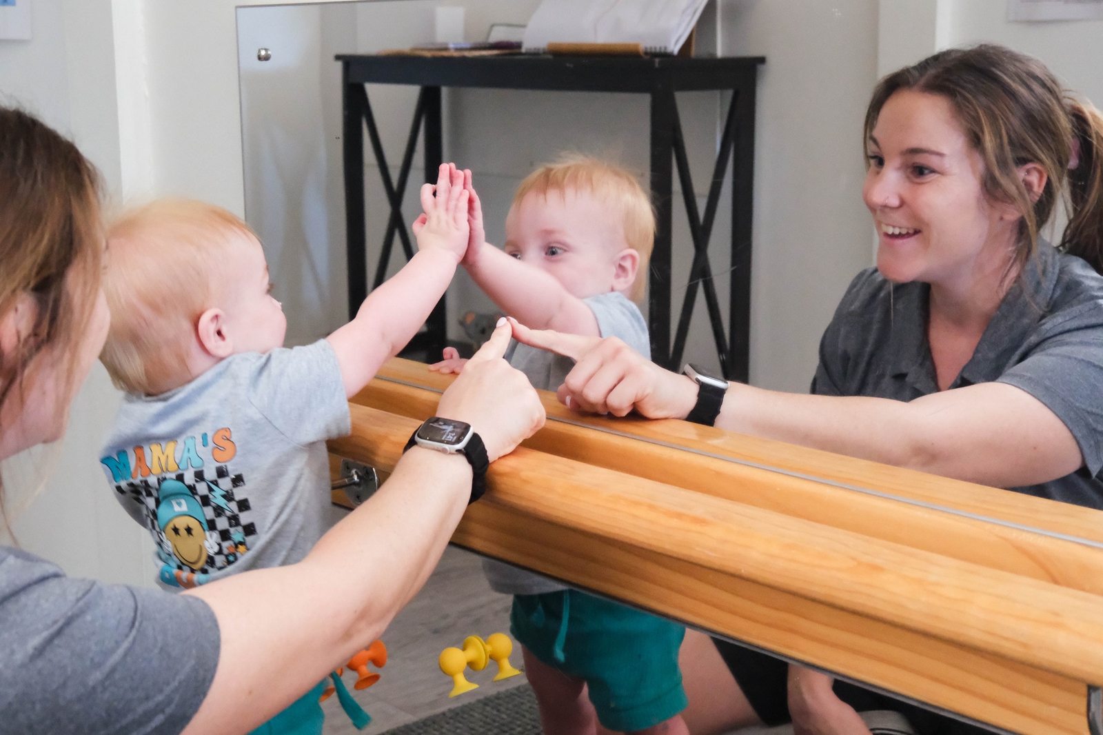 An educator engaging with young children beside a mirror at Expeditions Raceview