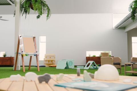 An indoor play area with an easel and open-ended materials at Expeditions Raceview 2