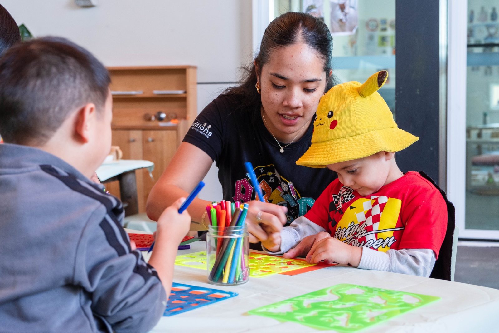 An educator supporting children with drawing at Expeditions Underwood