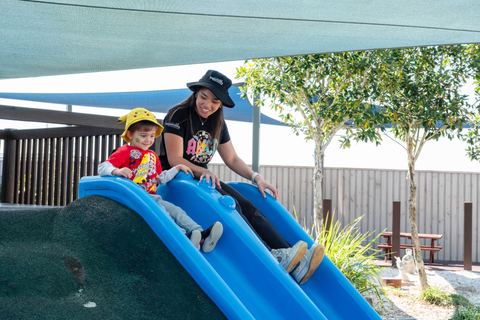 An educator and children on an outdoor slide at Expeditions Underwood