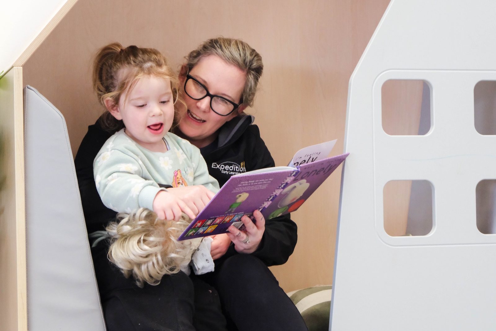 An educator reading with a child at Expeditions Officer